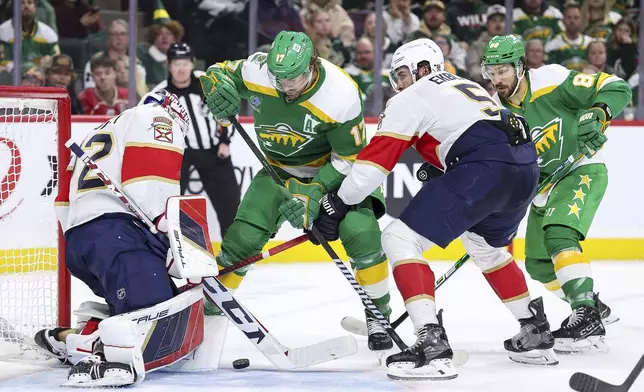 Minnesota Wild left wing Marcus Foligno, middle left, and Florida Panthers defenseman Aaron Ekblad (5) compete for the puck as Panthers goaltender Sergei Bobrovsky defends his net during the first period of an NHL hockey game Wednesday, Dec. 18, 2024, in St. Paul, Minn. (AP Photo/Matt Krohn)