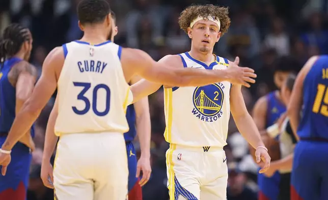 Golden State Warriors guard Stephen Curry, left, congratulates guard Brandin Podziemski after he made a basket and drew a foul shot against the Denver Nuggets in the first half of an Emirates NBA Cup basketball game Tuesday, Dec. 3, 2024, in Denver. (AP Photo/David Zalubowski)