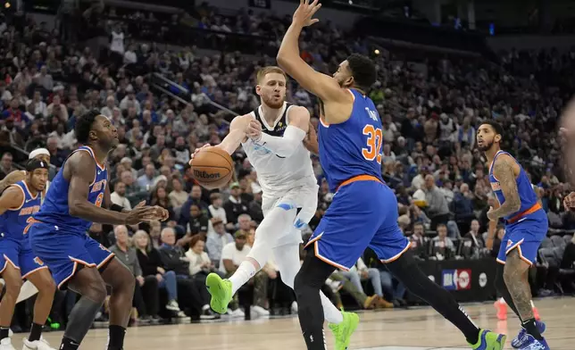 Minnesota Timberwolves guard Donte DiVincenzo (0) looks to pass as New York Knicks center Karl-Anthony Towns (32) defends during the first half of an NBA basketball game, Thursday, Dec. 19, 2024, in Minneapolis. (AP Photo/Abbie Parr)