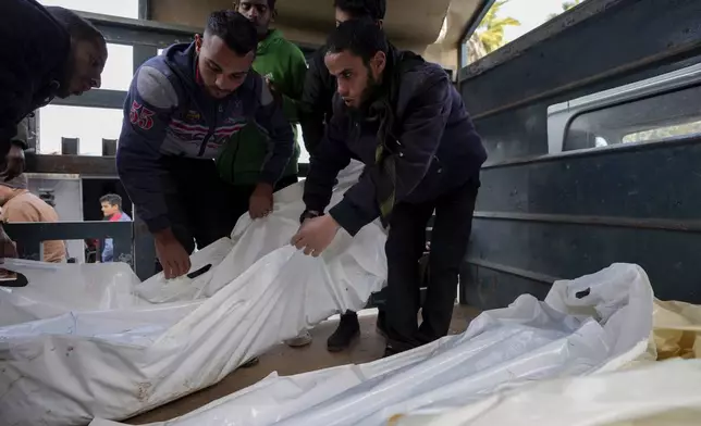 Palestinians carry white sacks containing the bodies of those killed in overnight Israeli airstrikes on the Maghazi refugee camp, at Al-Aqsa Hospital, in Deir al-Balah, central Gaza Strip, Saturday, Dec. 28, 2024. (AP Photo/Abdel Kareem Hana)