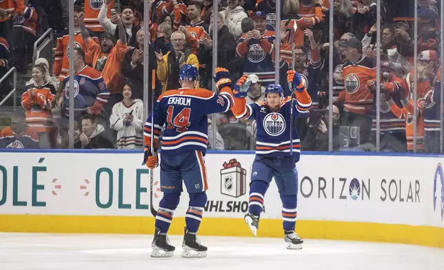 Edmonton Oilers' Mattias Ekholm (14) and Jeff Skinner (53) celebrate a goal against the Vegas Golden Knights during the third period of an NHL game in Edmonton, Alberta, Saturday, Dec. 14, 2024. (Jason Franson/The Canadian Press via AP)