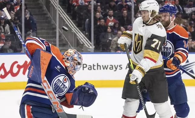 Vegas Golden Knights' William Karlsson (71) and Edmonton Oilers' Mattias Ekholm (14) battle in front as goalie Stuart Skinner (74) makes the save during the third period of an NHL game in Edmonton, Alberta, Saturday, Dec. 14, 2024. (Jason Franson/The Canadian Press via AP)