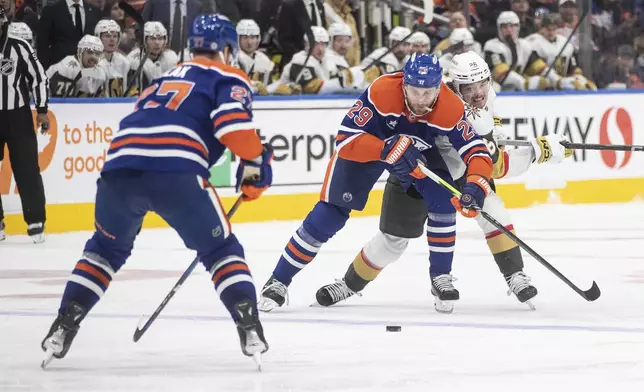 Vegas Golden Knights' Alexander Holtz (26) and Edmonton Oilers' Leon Draisaitl (29) battle for the puck during the third period of an NHL game in Edmonton, Alberta, Saturday, Dec. 14, 2024. (Jason Franson/The Canadian Press via AP)