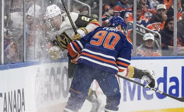 Vegas Golden Knights' Zach Whitecloud (2) is checked by Edmonton Oilers' Corey Perry (90) during the second period of an NHL game in Edmonton, Alberta, Saturday, Dec. 14, 2024. (Jason Franson/The Canadian Press via AP)