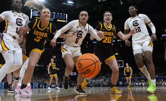 FILE - South Carolina guard Tessa Johnson (5) fights for a loose ball with Iowa guard Sydney Affolter (3) and guard Kate Martin (20) during the second half of the Final Four college basketball championship game in the women's NCAA Tournament, Sunday, April 7, 2024, in Cleveland. (AP Photo/Morry Gash, File)