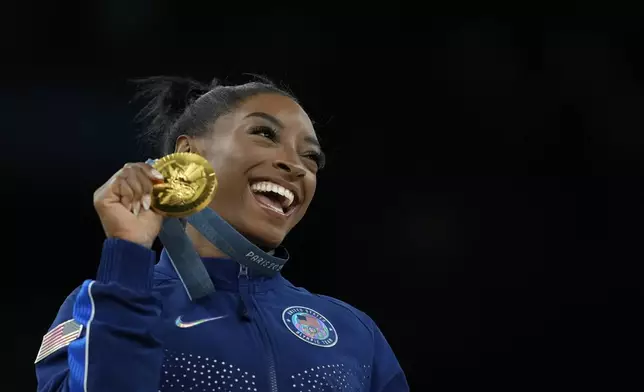 FILE -0 Simone Biles, of the United States, celebrates after winning the gold medal at the medal ceremony during the women's artistic gymnastics individual vault finals at Bercy Arena at the 2024 Summer Olympics, Saturday, Aug. 3, 2024, in Paris, France. (AP Photo/Francisco Seco, File)