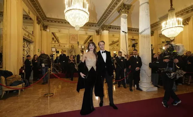 Etoiles Nicoletta Manni, left, and Timofej Andrijashenko pose for photographers as they arrive at Milan's Opera House La Scala, northern Italy, for the opening of the 2024-25 season featuring Giuseppe Verdi's 'La Forza del destino', Saturday, Dec. 7, 2024. (AP Photo/Luca Bruno)