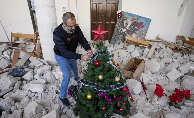 Georges Elia decorates a Christmas tree inside St. George Melkite Catholic Church, that was destroyed by Israeli airstrike, in the town of Dardghaya in southern Lebanon, Sunday, Dec. 22, 2024. (AP Photo/Hassan Ammar)