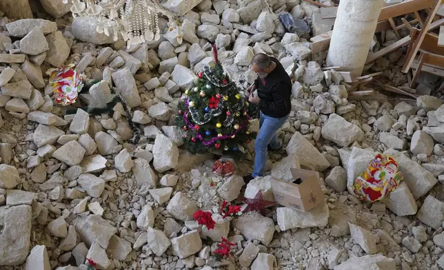 Georges Elia decorates a Christmas tree inside St. George Melkite Catholic Church, that was destroyed by Israeli airstrike, in the town of Dardghaya in southern Lebanon, Sunday, Dec. 22, 2024. (AP Photo/Hassan Ammar)