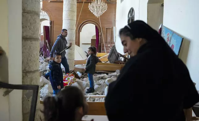 A christian man rings the bells next to a Christmas tree that has been decorated inside St. George Melkite Catholic Church in the town of Dardghaya in southern Lebanon, Sunday, Dec. 22, 2024. (AP Photo/Hassan Ammar)