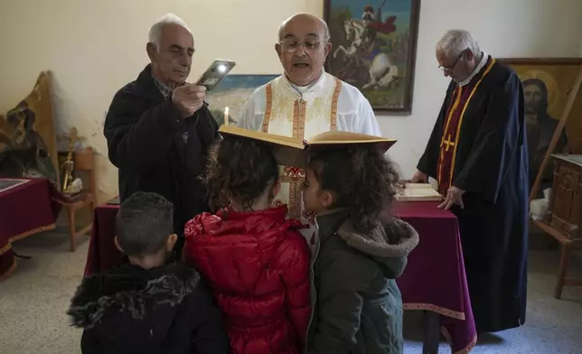 Priest Maurice el Khoury, center, leads the Sunday Mass inside a room that is usually used as a residence for visiting bishops next to his St. George Melkite Catholic church, that was destroyed by Israeli airstrike, in the town of Dardghaya in southern Lebanon, Sunday, Dec. 22, 2024. (AP Photo/Hassan Ammar)