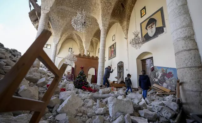 A christian man rings the bells next to a Christmas tree that has been decorated inside St. George Melkite Catholic Church in the town of Dardghaya in southern Lebanon, Sunday, Dec. 22, 2024. (AP Photo/Hassan Ammar)