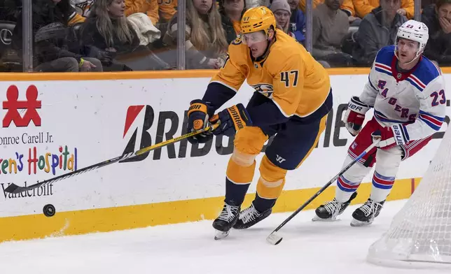 Nashville Predators right wing Michael McCarron (47) skates the puck past New York Rangers defenseman Adam Fox (23) during the second period of an NHL hockey game Tuesday, Dec. 17, 2024, in Nashville, Tenn. (AP Photo/George Walker IV)