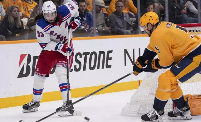 New York Rangers center Mika Zibanejad (93) hits the puck past Nashville Predators defenseman Kevin Gravel (5) during the first period of an NHL hockey game Tuesday, Dec. 17, 2024, in Nashville, Tenn. (AP Photo/George Walker IV)