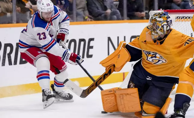 Nashville Predators goaltender Juuse Saros (74) blocks a shot on goal against the New York Rangers defenseman Adam Fox (23) during the first period of an NHL hockey game Tuesday, Dec. 17, 2024, in Nashville, Tenn. (AP Photo/George Walker IV)