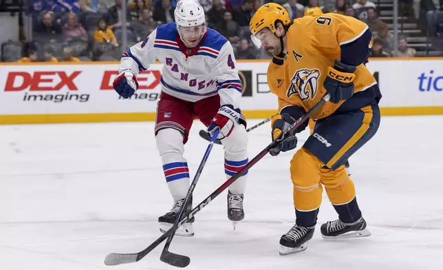 Nashville Predators left wing Filip Forsberg (9) skates the puck past New York Rangers defenseman Braden Schneider (4) during the second period of an NHL hockey game Tuesday, Dec. 17, 2024, in Nashville, Tenn. (AP Photo/George Walker IV)