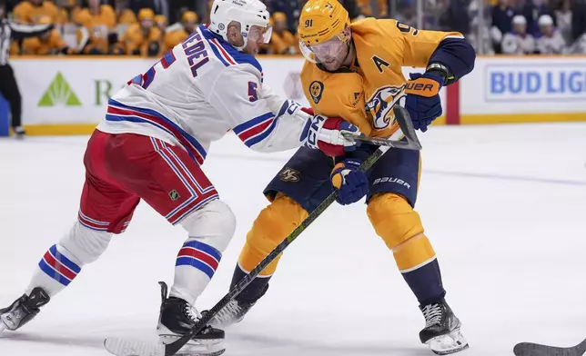 Nashville Predators center Steven Stamkos (91) skate the puck past New York Rangers defenseman Chad Ruhwedel (5) during the second period of an NHL hockey game Tuesday, Dec. 17, 2024, in Nashville, Tenn. (AP Photo/George Walker IV)