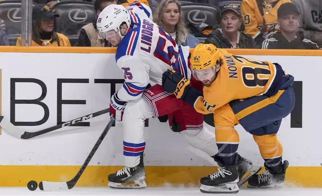 New York Rangers defenseman Ryan Lindgren (55) and Nashville Predators center Tommy Novak (82) chase the puck during the second period of an NHL hockey game Tuesday, Dec. 17, 2024, in Nashville, Tenn. (AP Photo/George Walker IV)