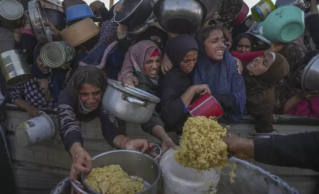 Palestinian girls struggle as they get donated food at a distribution center in Khan Younis, Gaza Strip, on Friday, Dec. 6, 2024. (AP Photo/Abdel Kareem Hana)