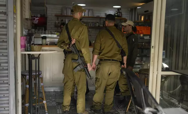 Israeli soldiers shop in a coffee store in northern Israel near the Lebanon border, Friday, Dec. 6, 2024. (AP Photo/Matias Delacroix)