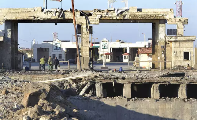 People cross through the destroyed crossing border point between Lebanon and Syria which hit by an Israeli airstrike, in Arida, north Lebanon, Friday, Dec. 6, 2024. (AP Photo)