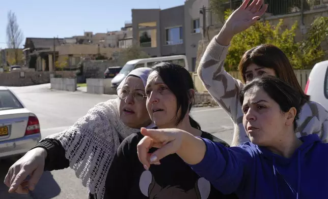 Soja Safadi, center, with her sisters, tries to see their other sister, Sawsan, who is inside the buffer zone near the "Alpha Line" that separates the Israeli-controlled Golan Heights from Syria, in the town of Majdal Shams, Wednesday, Dec. 18, 2024. (AP Photo/Matias Delacroix)