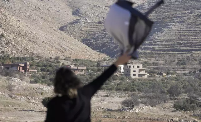 Salma Safadi waves to her sister, Sawsan, who is inside the buffer zone near the "Alpha Line" that separates the Israeli-controlled Golan Heights from Syria, in the town of Majdal Shams, Tuesday, Dec. 17, 2024. (AP Photo/Matias Delacroix)