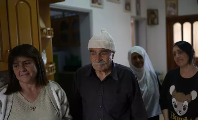 Ahmad Safadi, center, stands with his daughters after an interview about his other daughter, Sawsan, who lives inside the buffer zone near the "Alpha Line" that separates the Israeli-controlled Golan Heights from Syria, in the town of Majdal Shams, Wednesday, Dec. 18, 2024. (AP Photo/Matias Delacroix)