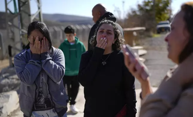 Safadi sisters Soha, left, and Salma, cry after speaking by phone with their sister, Sawsan, who is inside the buffer zone near the "Alpha Line" that separates the Israeli-controlled Golan Heights from Syria, in the town of Majdal Shams, Tuesday, Dec. 17, 2024. (AP Photo/Matias Delacroix)