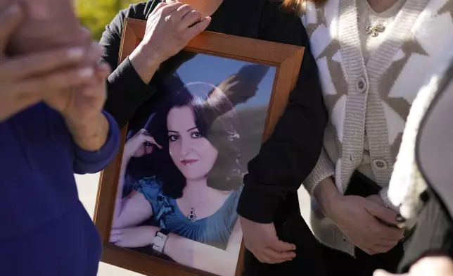 Soha Safadi holds a portrait of her sister, Sawsan, who lives inside the buffer zone near the "Alpha Line" that separates the Israeli-controlled Golan Heights from Syria, in the town of Majdal Shams, Wednesday, Dec. 18, 2024. (AP Photo/Matias Delacroix)