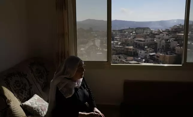 Samar Safadi sits next to a window after speaking by phone with her sister, Sawsan, who lives inside the buffer zone near the "Alpha Line" that separates the Israeli-controlled Golan Heights from Syria, in the town of Majdal Shams, Wednesday, Dec. 18, 2024. (AP Photo/Matias Delacroix)