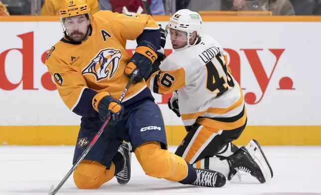 Nashville Predators left wing Filip Forsberg (9) passes the puck past Pittsburgh Penguins center Blake Lizotte (46) during the second period of an NHL hockey game Thursday, Dec. 19, 2024, in Nashville, Tenn. (AP Photo/George Walker IV)