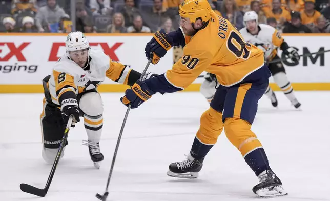 Nashville Predators center Ryan O'Reilly (90) shoots the puck past Pittsburgh Penguins left wing Michael Bunting (8) during the second period of an NHL hockey game Thursday, Dec. 19, 2024, in Nashville, Tenn. (AP Photo/George Walker IV)