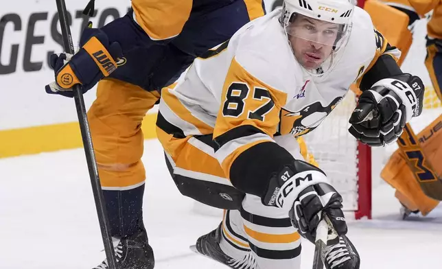 Pittsburgh Penguins center Sidney Crosby (87) hits the puck away from Nashville Predators center Ryan O'Reilly (90) during the third period of an NHL hockey game Thursday, Dec. 19, 2024, in Nashville, Tenn. The Penguins won 5-4 in overtime. (AP Photo/George Walker IV)