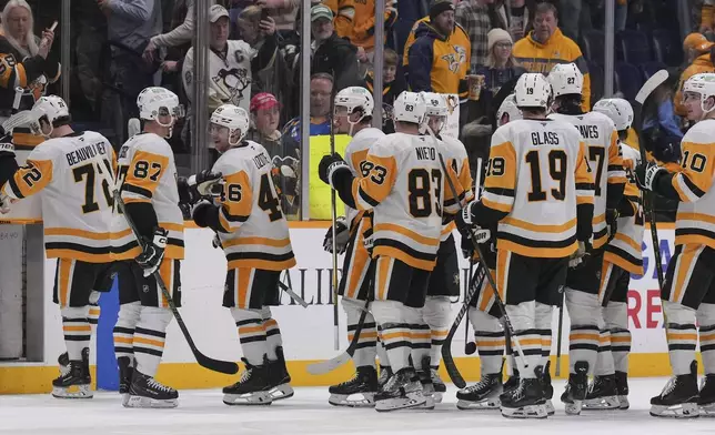 Members of the Pittsburgh Penguins celebrate the team's 5-4 overtime win against the Nashville Predators after an NHL hockey game Thursday, Dec. 19, 2024, in Nashville, Tenn. (AP Photo/George Walker IV)