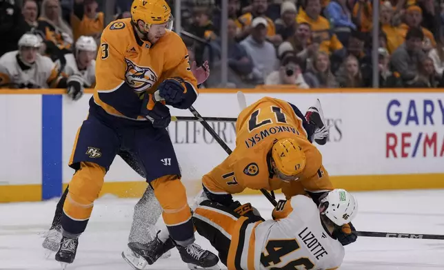 Nashville Predators center Mark Jankowski (17) hits Pittsburgh Penguins center Blake Lizotte (46) to the ice as Predators defenseman Jeremy Lauzon (3) looks on during the third period of an NHL hockey game Thursday, Dec. 19, 2024, in Nashville, Tenn. The Penguins won 5-4 in overtime. (AP Photo/George Walker IV)