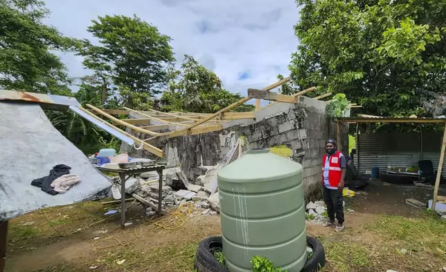 In this photo released by Vanuatu Red Cross Society, a Red Cross volunteer stands beside a damaged house in Efate, Vanuatu, Thursday, Dec. 19, 2024, following a powerful earthquake that struck just off the coast of Vanuatu in the South Pacific Ocean. (Vanuatu Red Cross Society via AP)