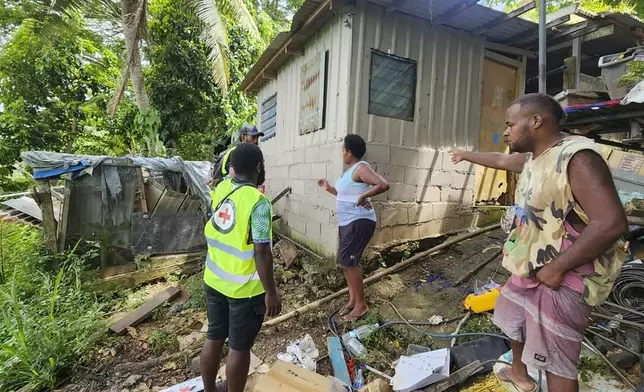 In this photo released by Vanuatu Red Cross Society, Red Cross volunteers assist locals as they inspect their damaged house in Efate, Vanuatu, Thursday, Dec. 19, 2024, following a powerful earthquake that struck just off the coast of Vanuatu in the South Pacific Ocean. (Vanuatu Red Cross Society via AP)