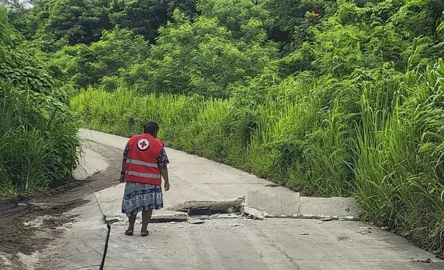 In this photo released by Vanuatu Red Cross Society, a Red Cross volunteer inspects a damaged road in Efate, Vanuatu, Thursday, Dec. 19, 2024, following a powerful earthquake that struck just off the coast of Vanuatu in the South Pacific Ocean. (Vanuatu Red Cross Society via AP)