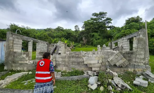 In this photo released by Vanuatu Red Cross Society, a Red Cross volunteer inspects a damaged house in Efate, Vanuatu, Thursday, Dec. 19, 2024, following a powerful earthquake that struck just off the coast of Vanuatu in the South Pacific Ocean. (Vanuatu Red Cross Society via AP)