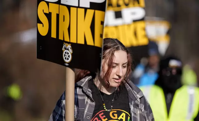 A pro-union demonstrator marches outside an Amazon warehouse, Friday, Dec. 20, 2024, in Alpharetta, Ga. (AP Photo/Mike Stewart)