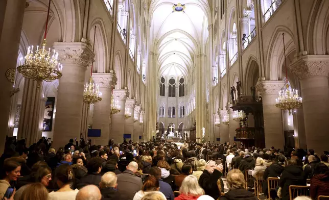 Faithful sit before the mass at Notre Dame Cathedral as the monuments hosts Christmas Eve services for the first time since a devastating 2019 fire, Tuesday, Dec. 24, 2024 in Paris. (AP Photo/Thomas Padilla)