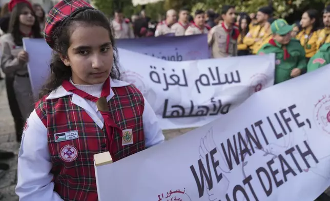 Palestinian scouts carry posters, one reads "Peace for Gaza and its people," while they march during Christmas Eve celebrations at the Church of the Nativity, traditionally recognized by Christians to be the birthplace of Jesus Christ, in the West Bank city of Bethlehem Tuesday, Dec. 24, 2024. (AP Photo/Nasser Nasser)