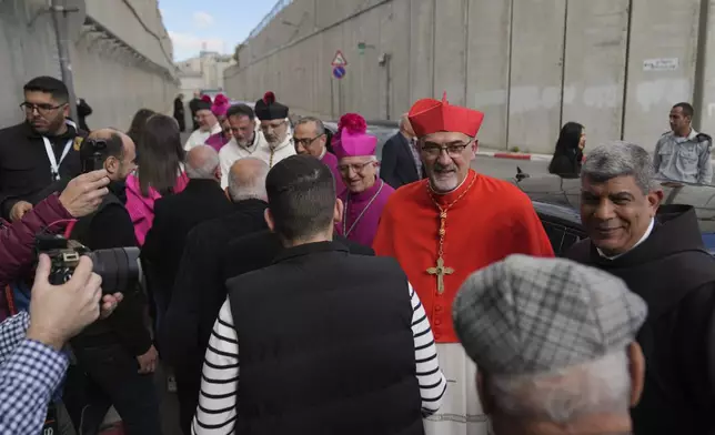 Archbishop Pierbattista Pizzaballa, the top Roman Catholic cleric in the Holy Land, is received by local community while crossing an Israeli military checkpoint from Jerusalem for Christmas Eve celebrations at the Church of the Nativity, traditionally recognized by Christians to be the birthplace of Jesus Christ, in the West Bank city of Bethlehem Tuesday, Dec. 24, 2024. (AP Photo/Nasser Nasser)