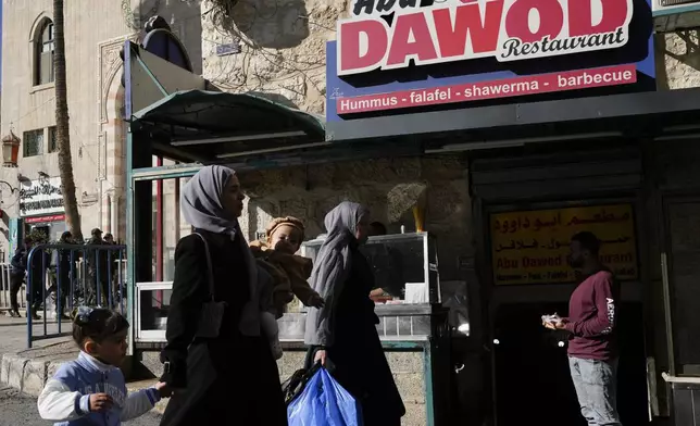 People walk past a restaurant near the Church of the Nativity, traditionally believed to be the birthplace of Jesus, on Christmas Eve, in the West Bank city of Bethlehem, Tuesday, Dec. 24, 2024. (AP Photo/Matias Delacroix)