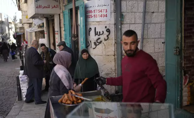 A woman buys street food near the Church of the Nativity, traditionally believed to be the birthplace of Jesus, on Christmas Eve, in the West Bank city of Bethlehem, Tuesday, Dec. 24, 2024. (AP Photo/Matias Delacroix)