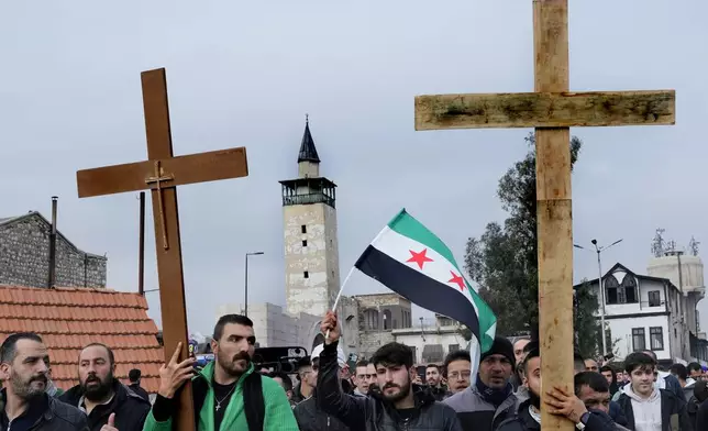 Syrian Christians carry crosses and shout slogans, as they march during a protest after a Christmas tree was set on fire in Hamah city on Sunday, in Damascus, Syria, Tuesday, Dec. 24, 2024.(AP Photo/Hussein Malla)