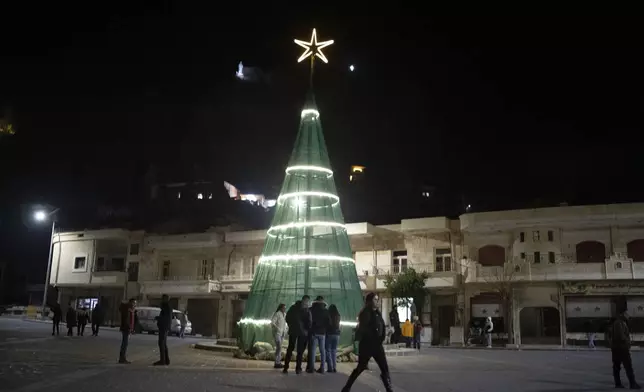 People walks past a Christmas tree after attending a Christmas mass at the church of St. George, in Maaloula, some 60 km northern Damascus, Syria, Tuesday, Dec. 24, 2024. (AP Photo/Leo Correa)