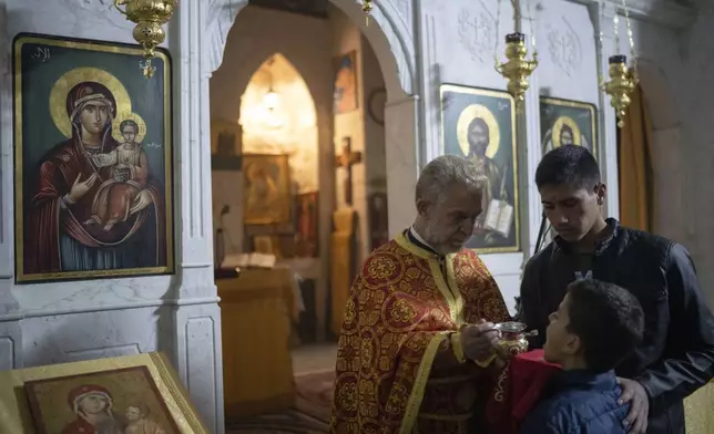 Priest Abuna Mata gives the communion during the Christmas mass in the Greek Orthodox convent Saint Takla, in Maaloula, some 60 km northern Damascus, Syria, Tuesday, Dec. 24, 2024. (AP Photo/Leo Correa)