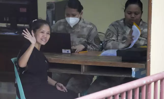 Mary Jane Veloso, a Filipino woman who spent almost 15 years in an Indonesian prison for drug trafficking and was nearly executed by firing squad in 2015, waves to reporters as she is processed at the Correctional Institution for Women in Mandaluyong, Philippines Wednesday, Dec. 18, 2024. (AP Photo/Aaron Favila)